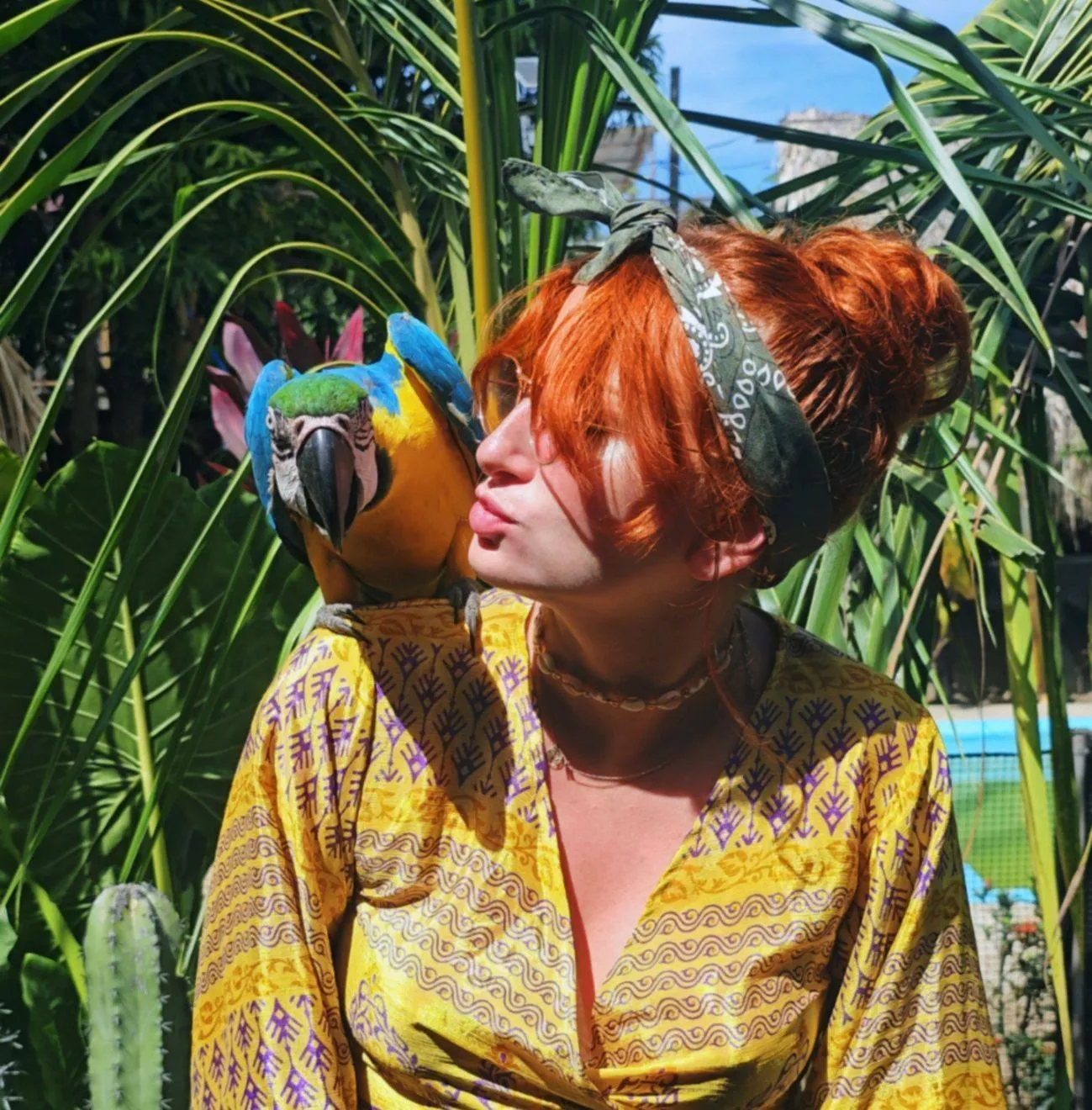 Kobieta z papugą na ramieniu w otoczeniu bujnej zieleni tropikalnej